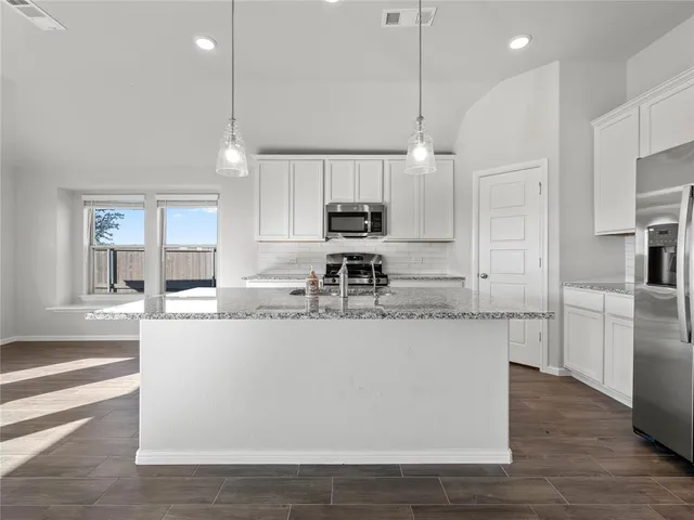 a kitchen with stainless steel appliances granite countertop a sink a stove and a refrigerator