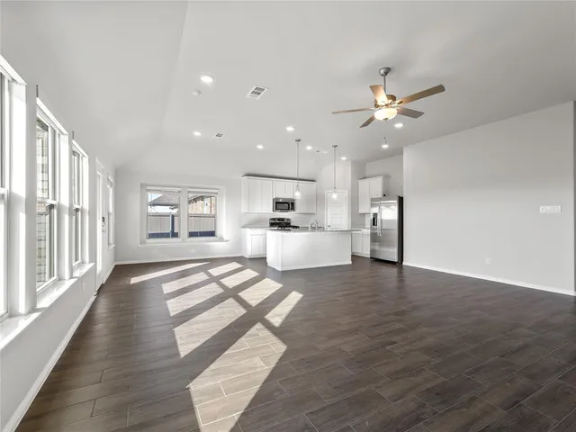 a view of a big room with wooden floor and a kitchen