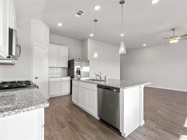 a kitchen with kitchen island a sink stainless steel appliances and wooden floor