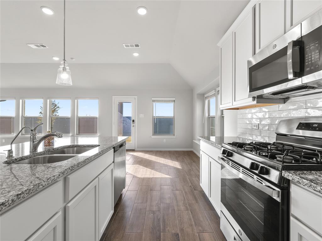 3301 Redbud Flower Trail Venus, TX 76084 - Photo 9 of 28 a kitchen with stainless steel appliances kitchen island granite countertop a sink a stove and a wooden floors