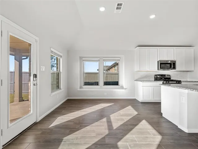 a kitchen with granite countertop a stove a sink and a refrigerator