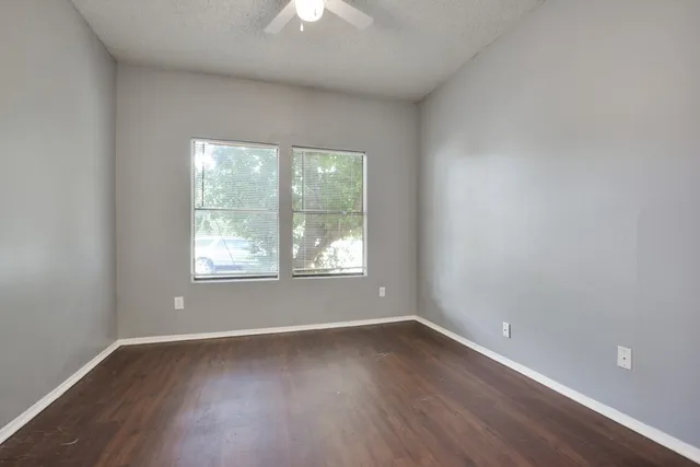 an empty room with wooden floor and windows