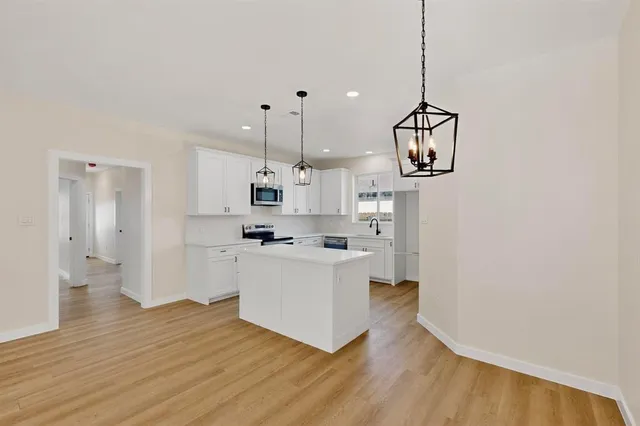 a kitchen with stainless steel appliances granite countertop a sink a stove and a wooden floor