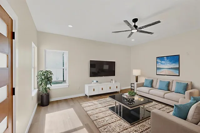 a living room with furniture a flat screen tv and a potted plant