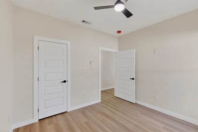 an empty room with wooden floor closet and ceiling fan