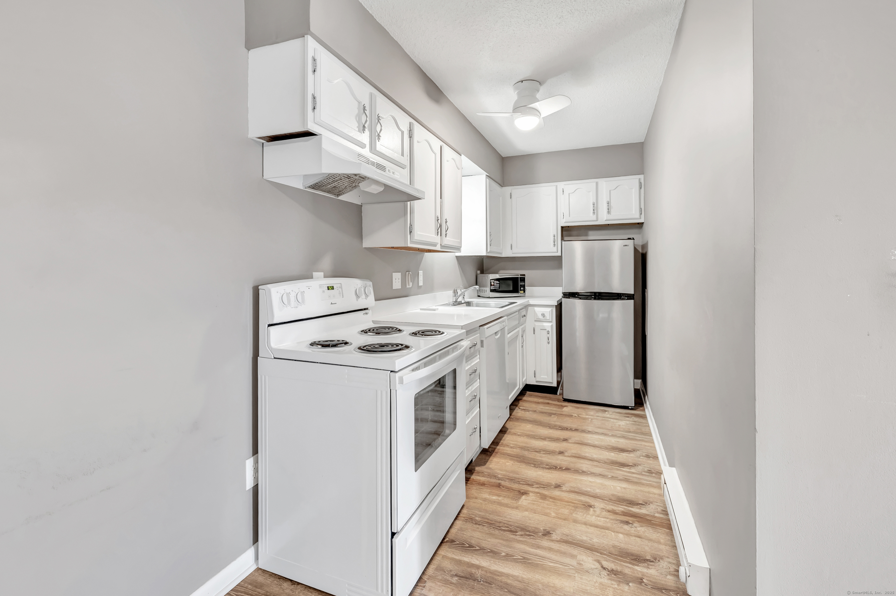 155 Short Beach Road, Unit 209 Stratford, CT 06615 - Photo 6 of 22 a kitchen with stainless steel appliances a white stove top oven a sink and a refrigerator