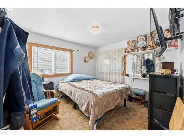 a bedroom with a bed and a flat tv screen on the dresser