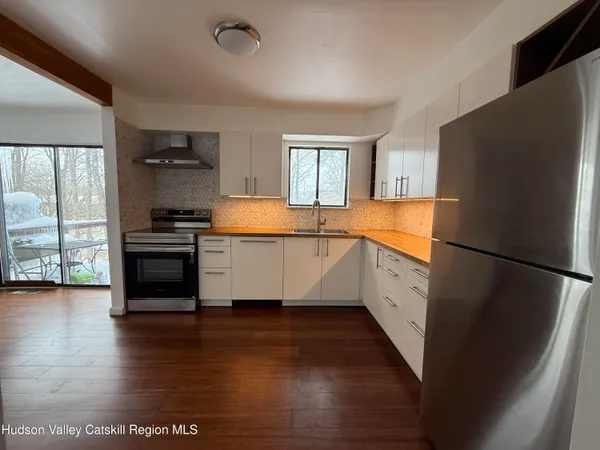 a kitchen with stainless steel appliances a refrigerator a stove a sink and a large window