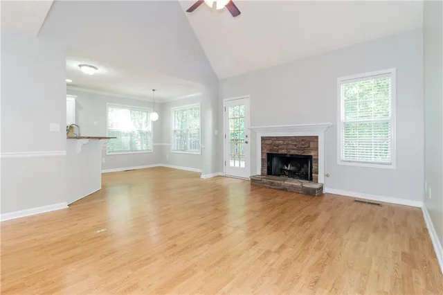 an empty room with wooden floor fireplace and windows