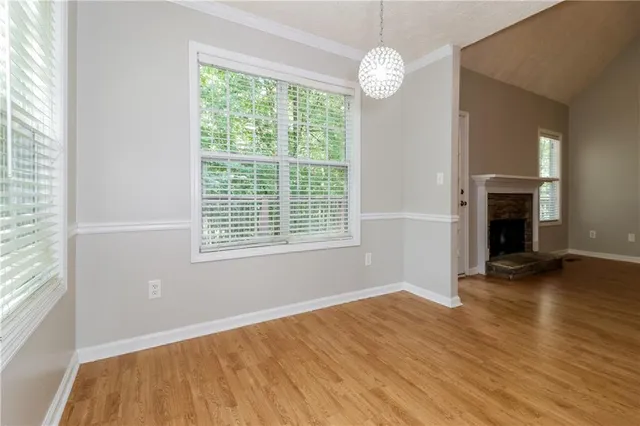 an empty room with wooden floor fireplace and windows