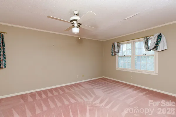 a view of a big room with windows and chandelier fan