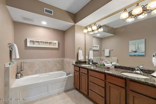 a bathroom with a granite countertop sink a large mirror and a bathtub