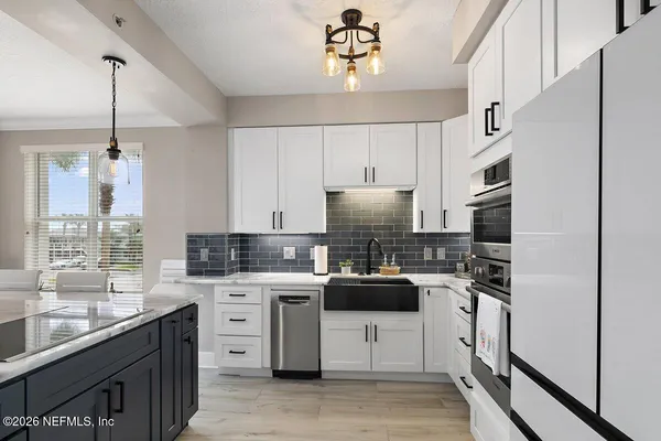 a kitchen with stainless steel appliances a sink a stove a refrigerator cabinets and a window