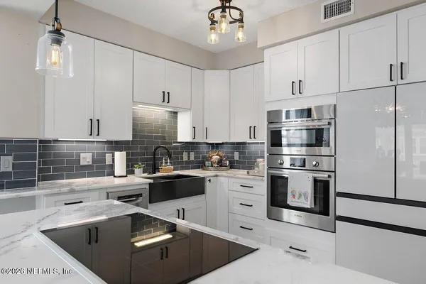 a kitchen with a sink stainless steel appliances and white cabinets