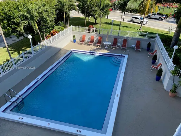 a view of a swimming pool with a lawn chairs and palm tree