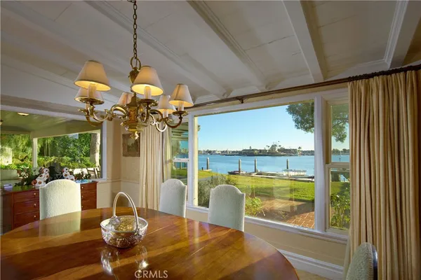a view of a dining room with furniture a chandelier and large windows