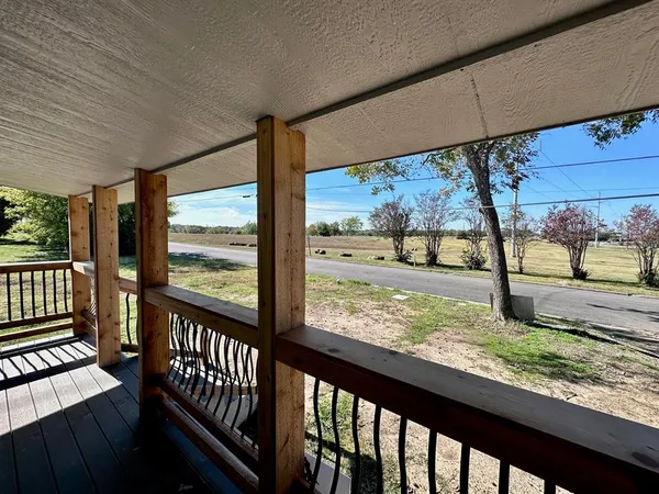 a view of a porch with wooden floor in front of a house