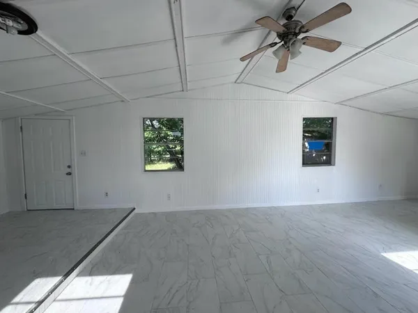 en empty room with ceiling fan and window