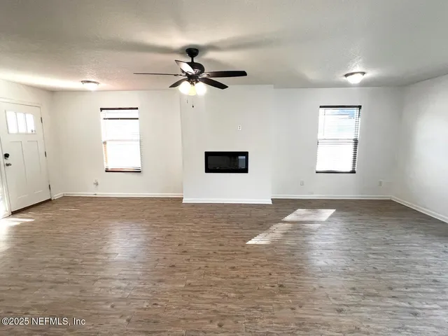 a view of empty room with window and ceiling fan