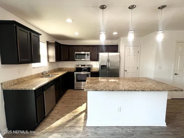 a large kitchen with a center island and stainless steel appliances