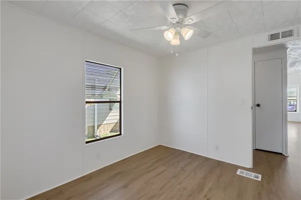 an empty room with windows and fan