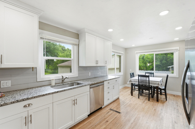 778 East 200 North Logan, UT 84321 - Photo 19 of 43 Modern kitchen featuring white shaker cabinetry, stainless steel appliances, granite countertops, and a subway tile backsplash