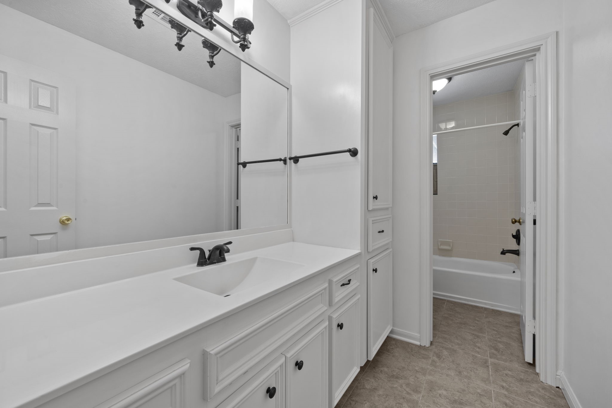 169 April Cove Montgomery, TX 77356 - Photo 7 of 39 Secondary bathroom, featuring tile floors, white cabinetry and countertops, a large mirror with vanity lights, and a shower/tub combo.