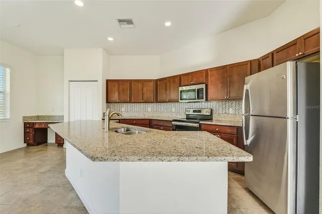 a kitchen with stainless steel appliances granite countertop a refrigerator a stove a sink a microwave and white cabinets