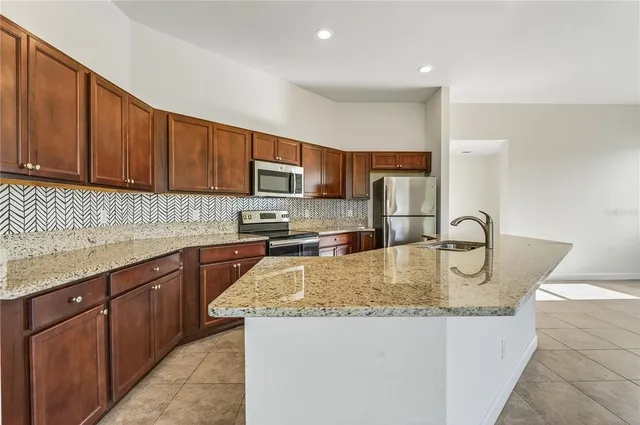 a kitchen with stainless steel appliances granite countertop a sink refrigerator and microwave