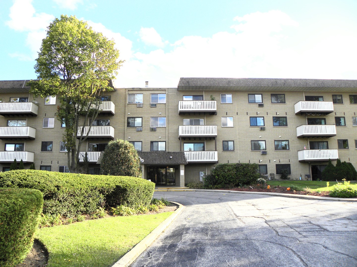 a front view of a building with a garden and plants