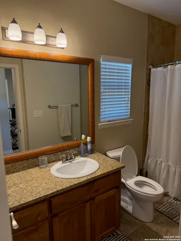 a bathroom with a granite countertop sink toilet and shower