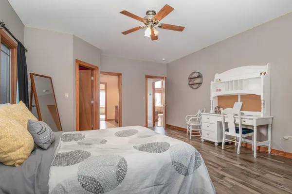 a bedroom with a bed a desk and chair with wooden floor