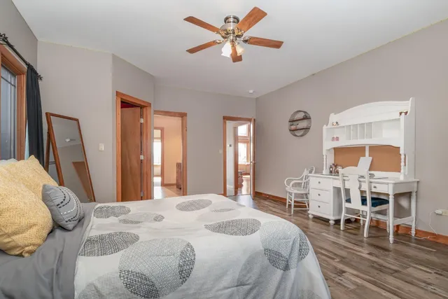 a bedroom with a bed a desk and chair with wooden floor
