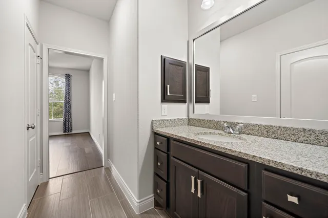 a bathroom with a granite countertop sink a toilet a mirror and shower