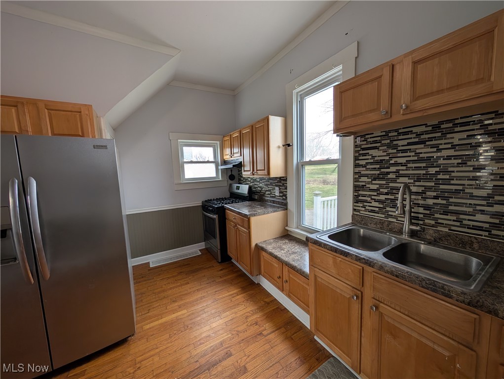10143 Pleasant Road Pleasant City, OH 43772 - Photo 11 of 32 Kitchen with stainless steel appliances, light wood-style flooring, ornamental molding, backsplash, and plenty of natural light
