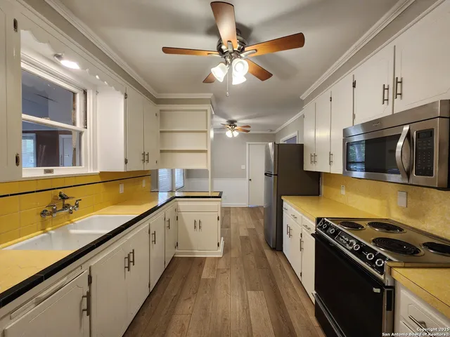 a kitchen with stainless steel appliances a sink dishwasher stove top oven and cabinets with wooden floor