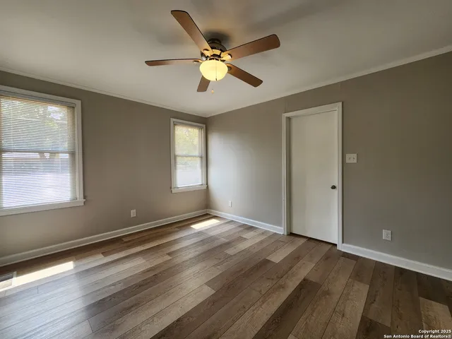 a view of an empty room with wooden floor and a window