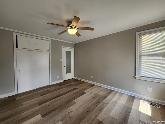 a view of an empty room with window and wooden floor