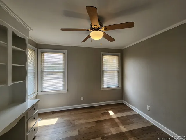 an empty room with wooden floor fan and windows
