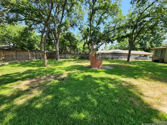 a backyard of a house with swimming pool and large trees