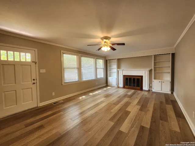 a view of an empty room with window and wooden floor