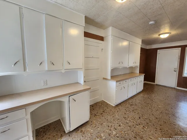 a kitchen that has a lot of white cabinets and wooden floor