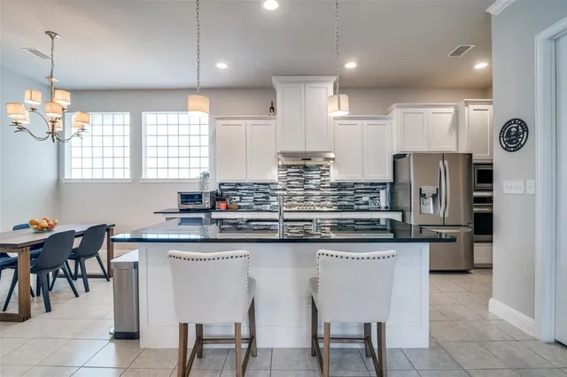 a kitchen with stainless steel appliances granite countertop a table chairs sink refrigerator and microwave