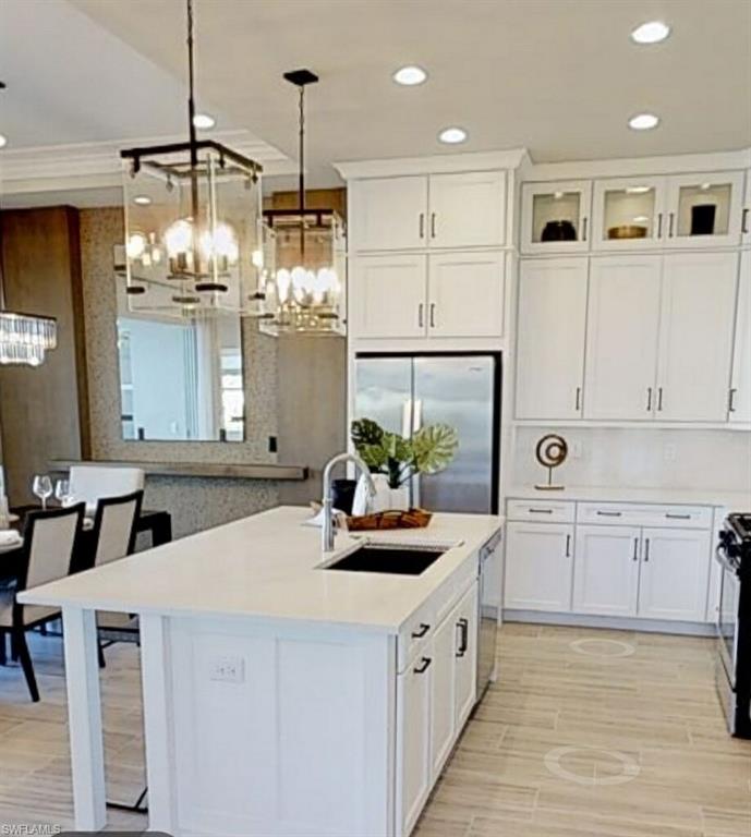 a kitchen with stainless steel appliances kitchen island granite countertop a sink dishwasher and white cabinets with wooden floor