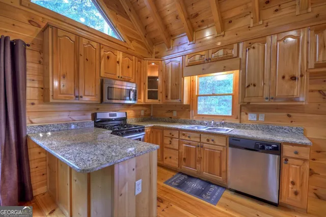 a kitchen with granite countertop kitchen island stainless steel appliances a sink stove and cabinets