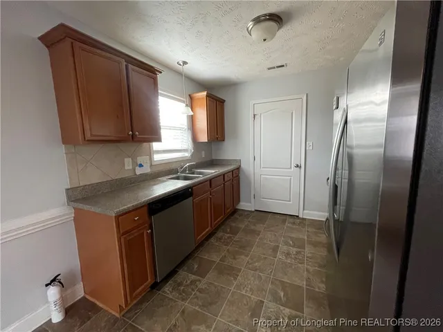 a kitchen with stainless steel appliances granite countertop a sink a stove and a refrigerator