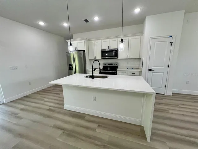 a kitchen with kitchen island a sink stainless steel appliances and cabinets