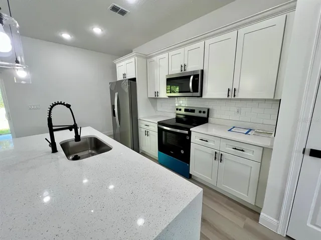 a kitchen with stainless steel appliances a microwave a sink a stove and a refrigerator