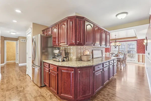 a kitchen with stainless steel appliances granite countertop a stove top oven a refrigerator a sink with island and chairs