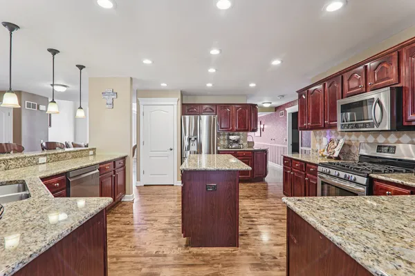 a large kitchen with stainless steel appliances granite countertop plenty wooden cabinets counter space a sink and a stove